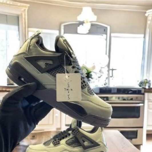 A1r Jord4n 4 retro olive green high-top sneakers with black mesh upper and TPU accents held up against blurred indoor background