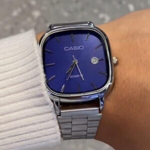 Cas1o square navy blue dial quartz watch with gold-tone hands and polished silver stainless steel bracelet worn on wrist