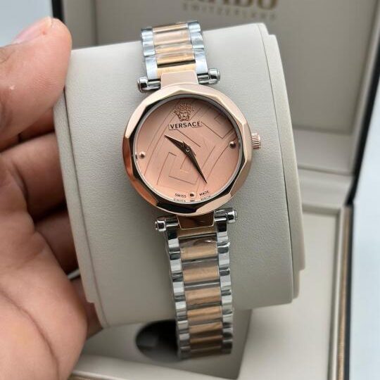 Vers4ce Greca Goddess Swiss Made watch with rose gold octagonal bezel, Greca pattern dial, Medusa logo and two-tone silver rose gold steel bracelet held in hand against Rado watch box